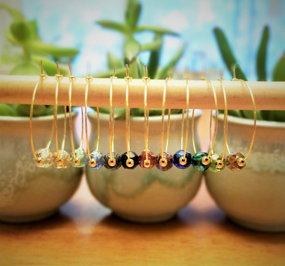 Clear, Pink, Light Turquoise, Light Sapphire Blue, Montana Blue, Garnet, Purple, Blue, Emerald, Olivine, and Copper luster crystal wine glass charms accented with 2mm and 4mm gold beads by Spirit & Vine