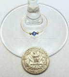 Mini blue crystal wine glass charms with two small silver beads on each side with a quarter for scale by Spirit & Vine